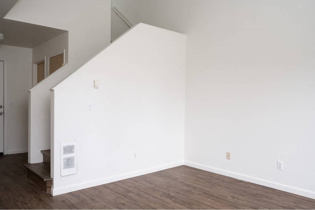 an empty room with white walls and a wood floor at Quail Run Apartments, Vancouver, WA 98684