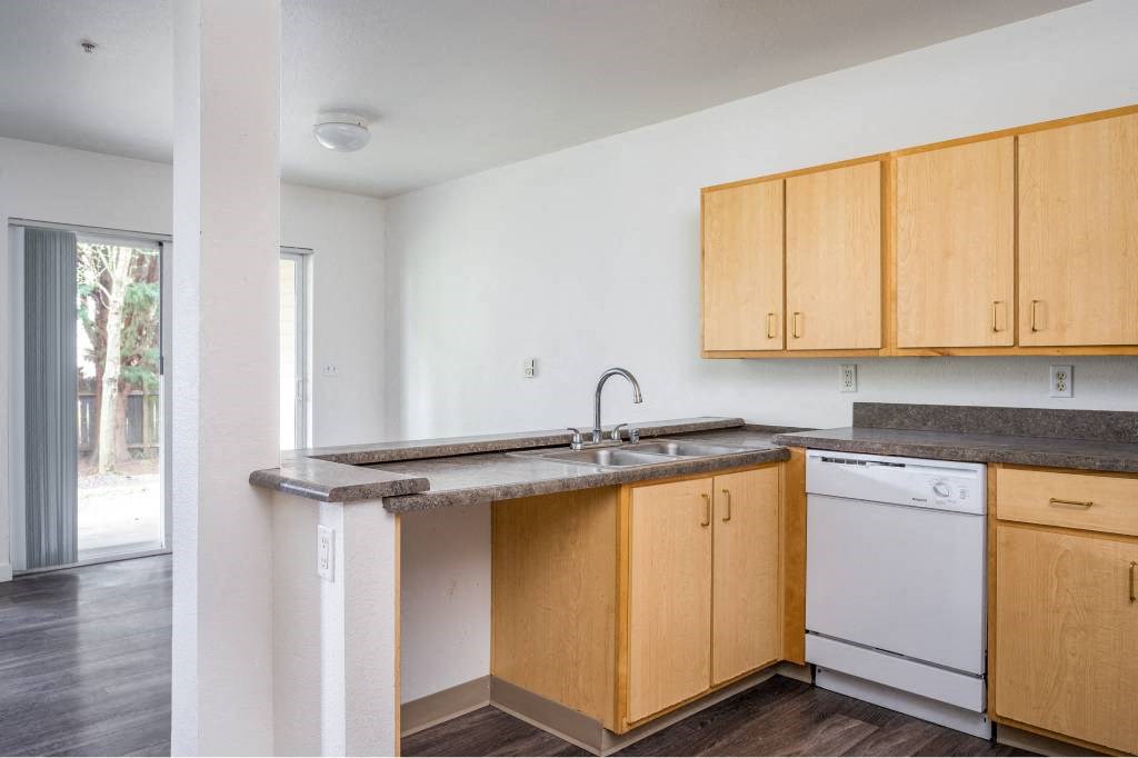 an empty kitchen with wooden cabinets and a sink at Quail Run Apartments, Vancouver, WA 98684
