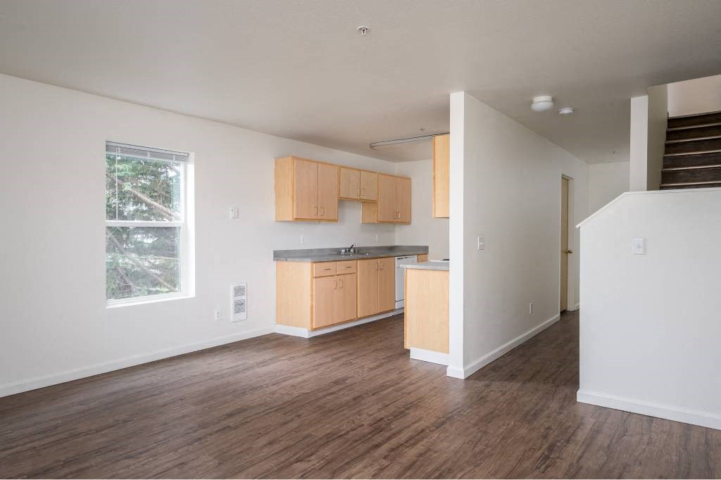 an empty living room and kitchen with wood floors at Quail Run Apartments, WA