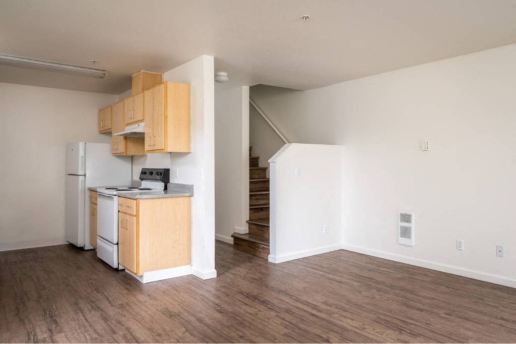 an empty living room with a kitchen and a staircase at Quail Run Apartments, Vancouver