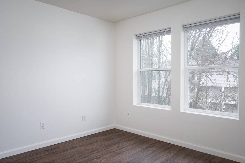 an empty room with two windows and a wooden floor at Quail Run Apartments, Vancouver, 98684