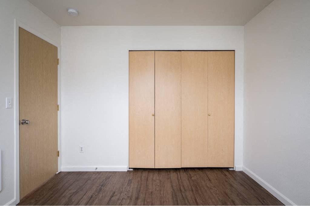 an empty room with white walls and wooden floors at Quail Run Apartments, Washington 98684