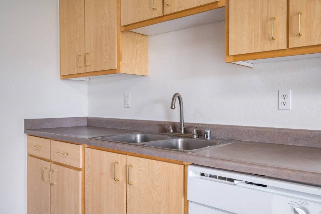 a kitchen with wooden cabinets and a sink at Quail Run Apartments, Vancouver, WA