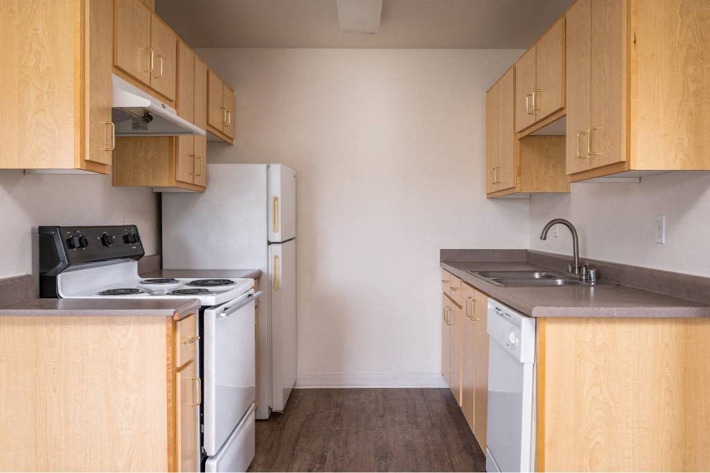 an empty kitchen with a stove refrigerator and sink at Quail Run Apartments, Vancouver, WA 98684