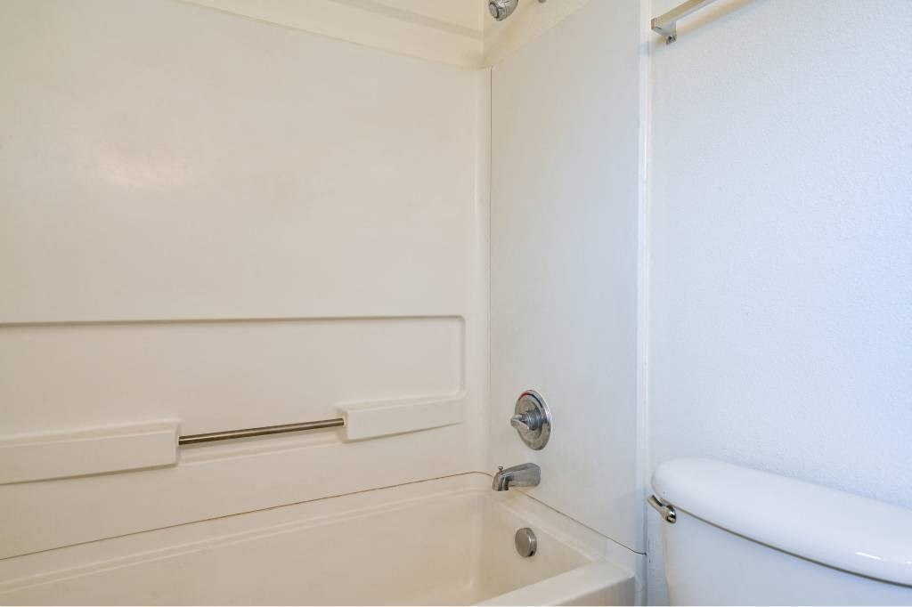 a white bathroom with a toilet and a bath tub at Quail Run Apartments, Vancouver, Washington