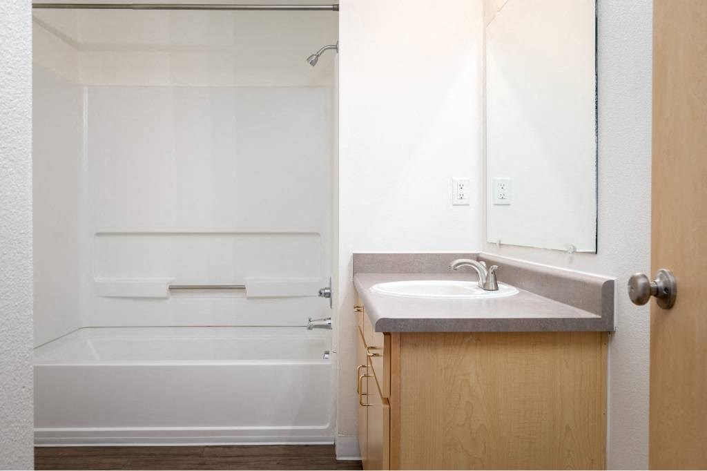 a bathroom with a sink and a shower and a mirror at Quail Run Apartments, WA
