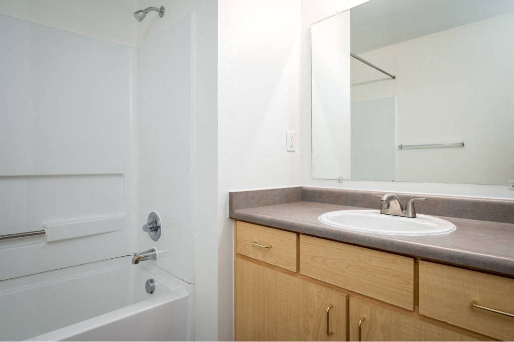 a bathroom with a sink and a shower and a mirror at Quail Run Apartments, Vancouver, 98684