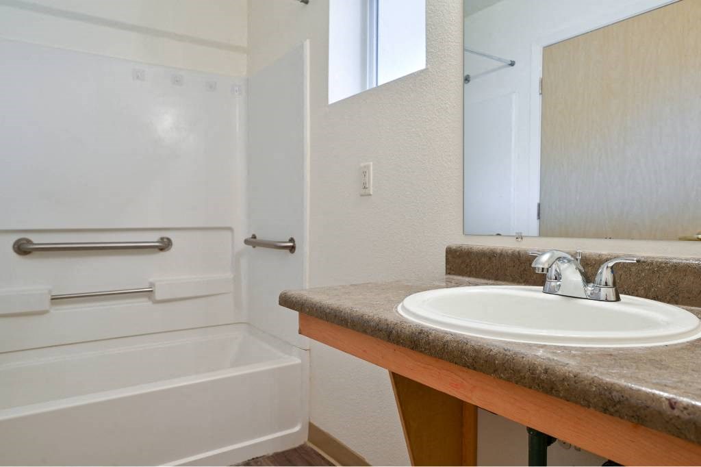 a bathroom with a sink and a tub and a mirror at Quail Run Apartments, Vancouver, WA