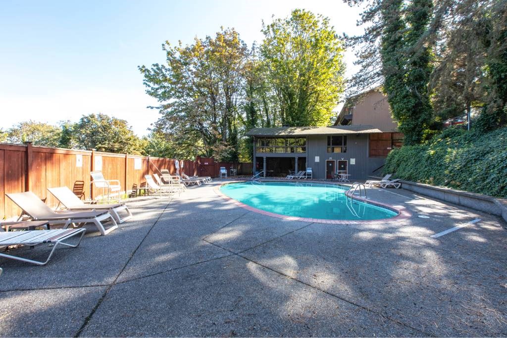 a backyard with a pool and chairs and a house at Whisperwood, Seattle, WA