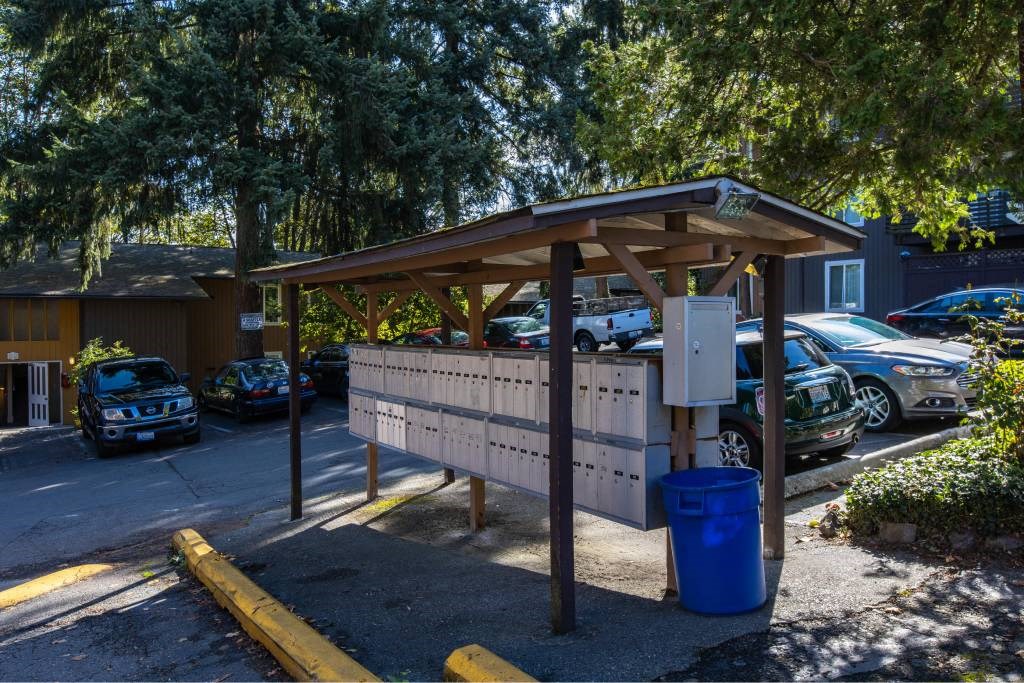 mail boxes in a parking lot with a trash can at Whisperwood, Seattle
