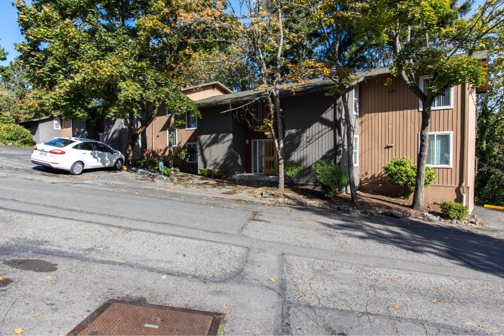 a car parked in front of a brown apartment at Whisperwood, Seattle, 98168
