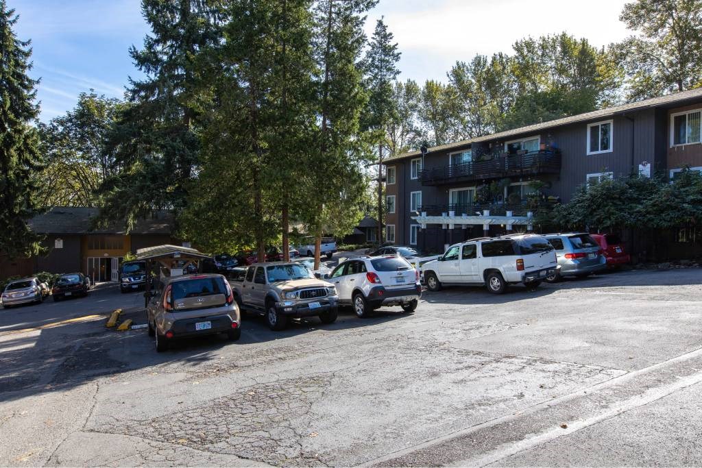 a parking lot filled with cars in front of a building at Whisperwood, Seattle, WA 98168