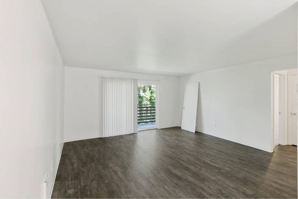an empty living room with white walls and wood floors at Whisperwood, Seattle, Washington