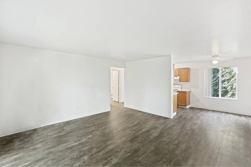 an empty living room with white walls and wood floors at Whisperwood, Seattle, 98168