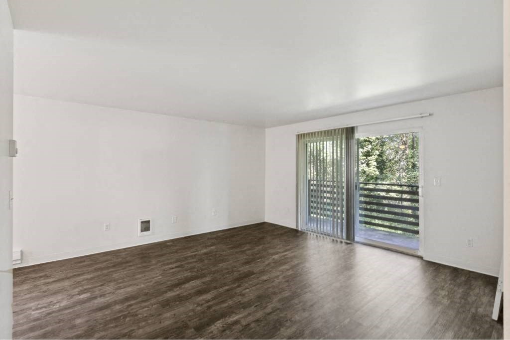an empty living room with a sliding glass door to a patio at Whisperwood, Seattle, 98168