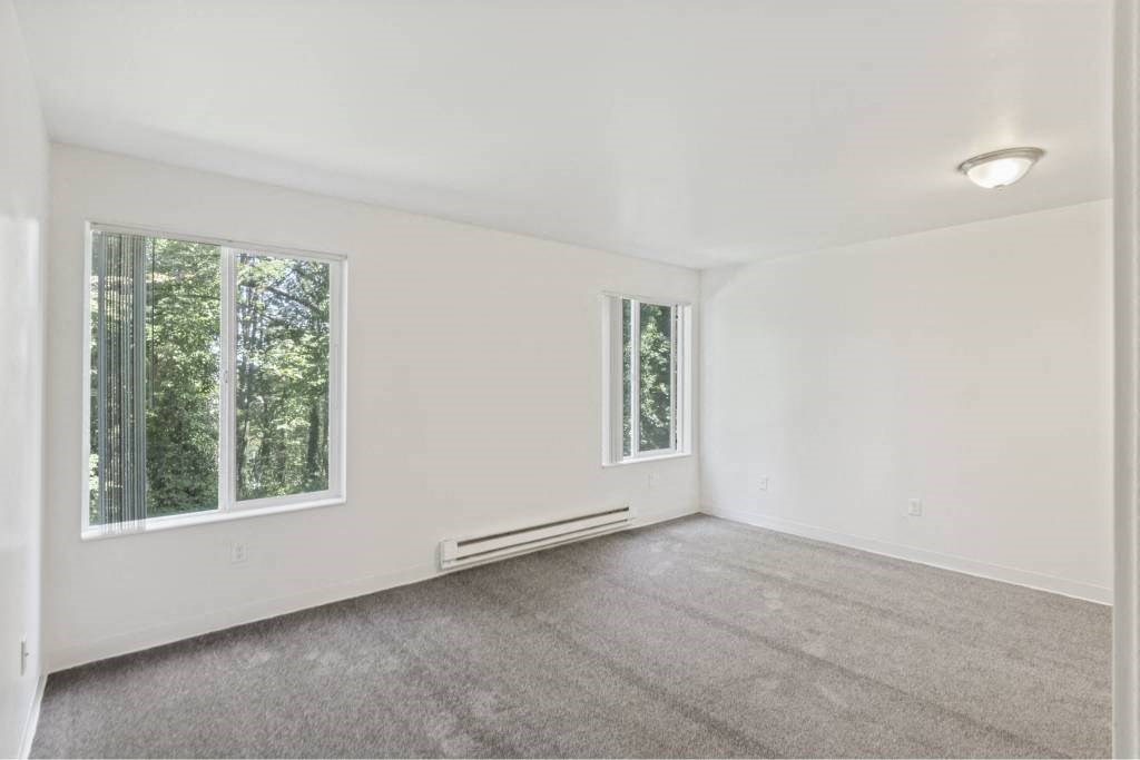 an empty living room with two windows and carpet at Whisperwood, Seattle, WA 98168