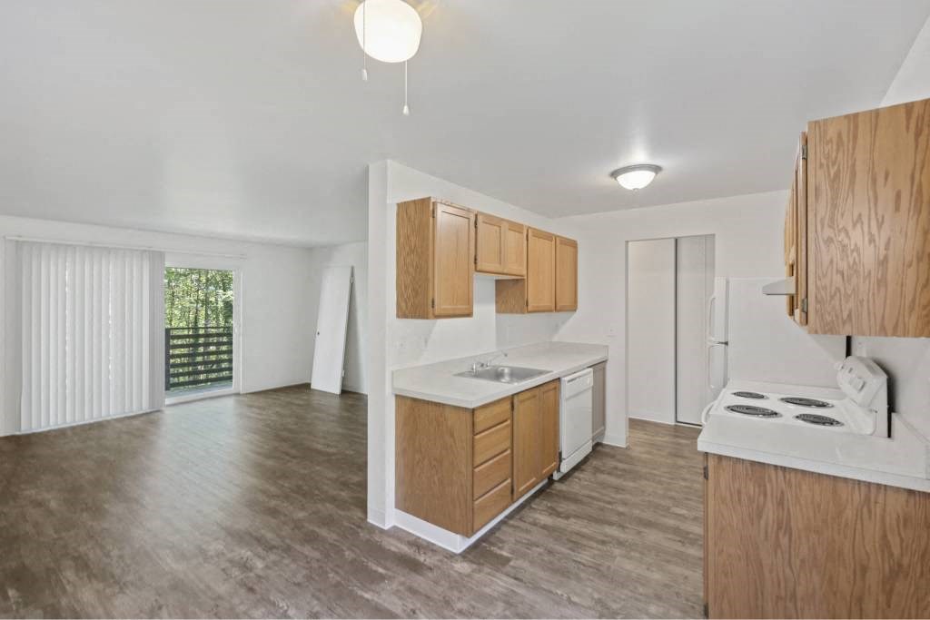 an empty kitchen with wooden cabinets and a white counter top at Whisperwood, Seattle, 98168