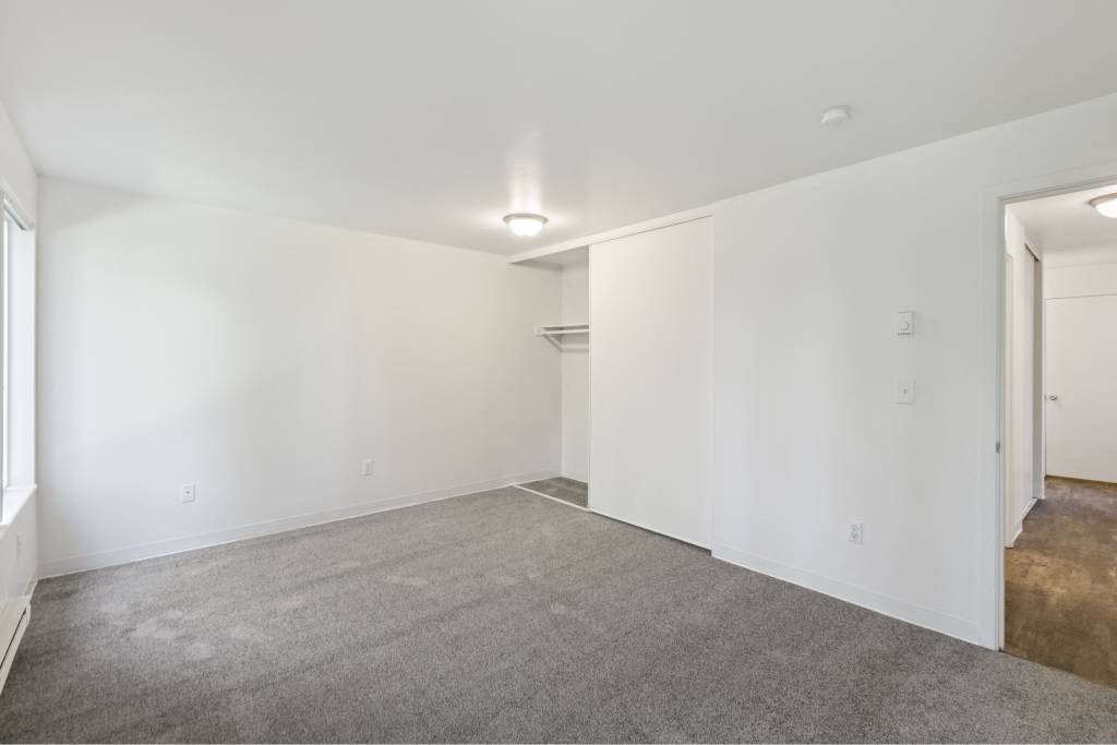 a bedroom with white walls and carpet and a closet at Whisperwood, Washington 98168