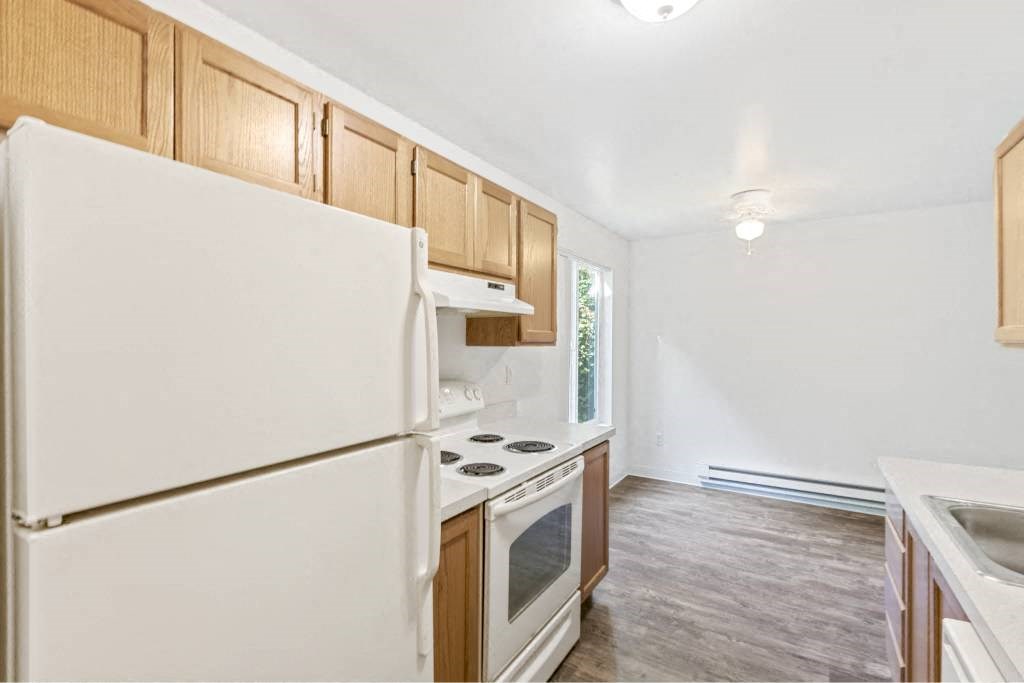a kitchen with white appliances and wooden cabinets at Whisperwood, Washington