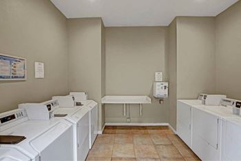 A laundry room with washers and dryers at The Henley Apartments, California