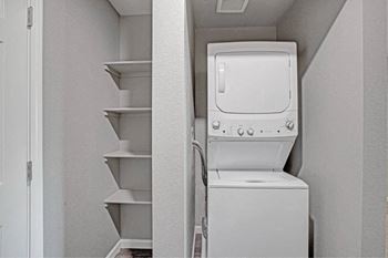 A white washing machine is in a small laundry room at The Henley Apartments, Suisun City, 94585