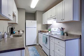 A kitchen with white appliances and cabinets at The Henley Apartments, Suisun City, CA