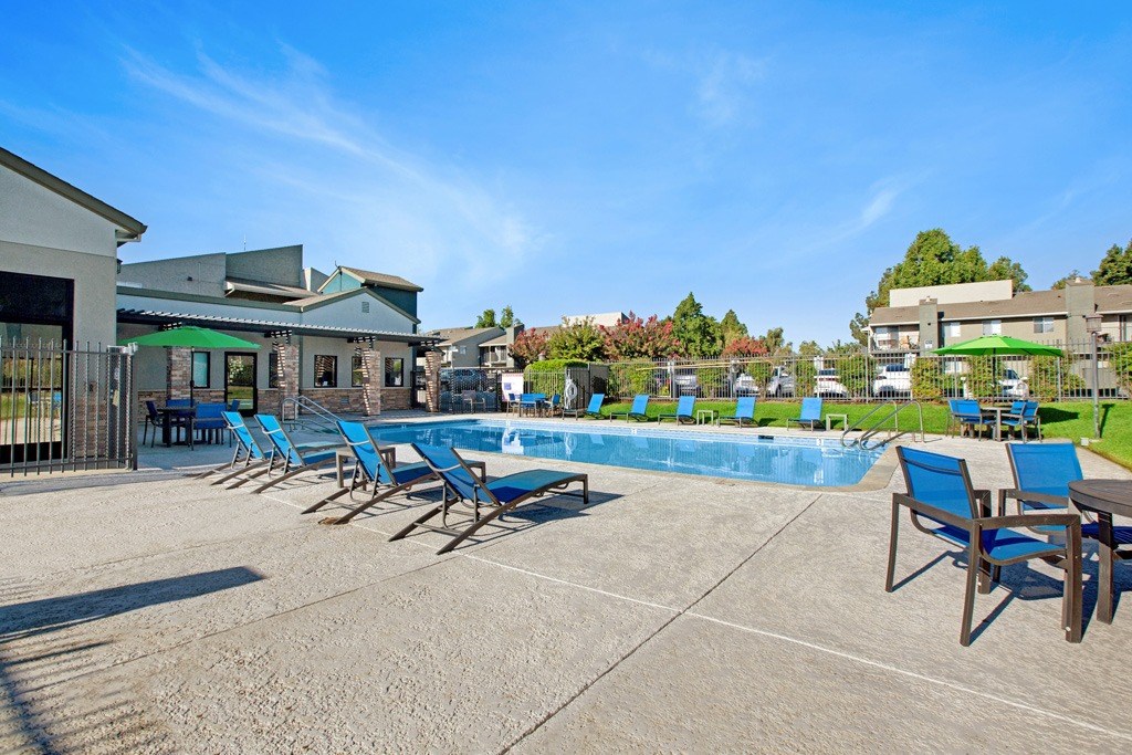 A pool area with sun loungers and a building in the background. A pool area with sun loungers and a building in the background at The Henley Apartments, Suisun City, CA
