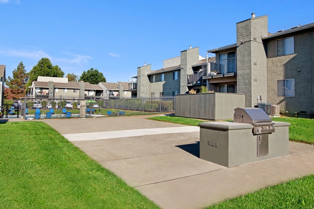 A concrete structure sits in the middle of a grassy area in front of apartment buildings at The Henley Apartments, Suisun City, CA