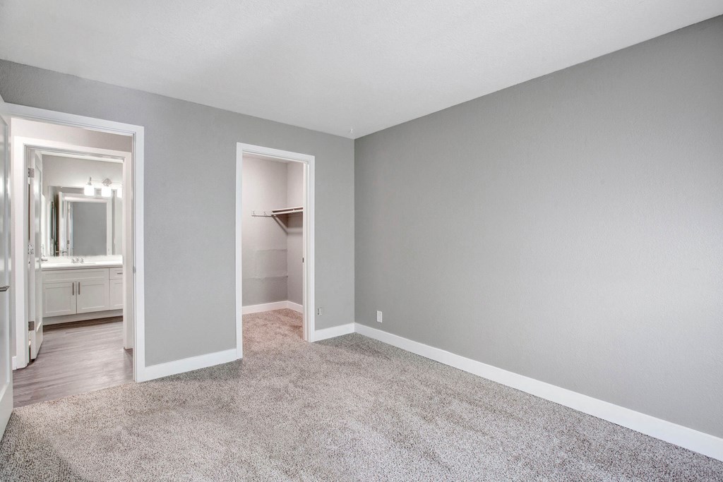 A room with a carpeted floor and a closet with a mirror at The Henley Apartments, California