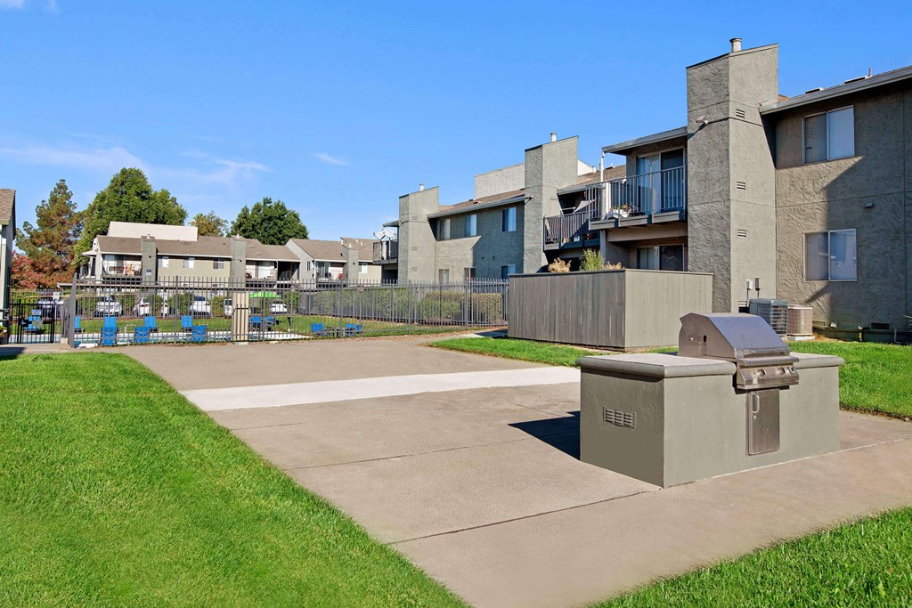 A concrete structure sits in the middle of a grassy area in front of apartment buildings at The Henley Apartments, Suisun City, 94585