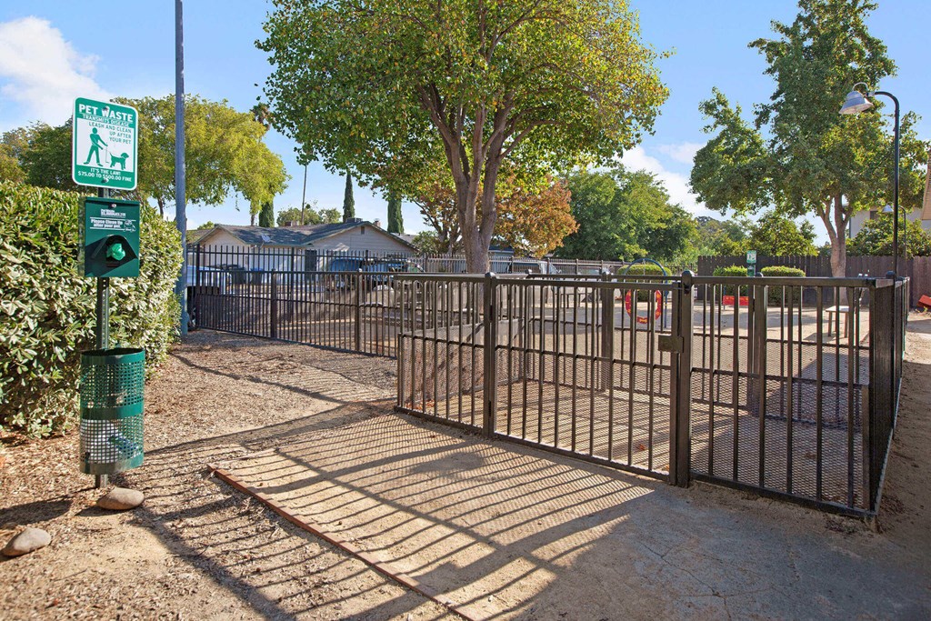 A gated entrance to a park with a sign for a walking trail at The Henley Apartments, Suisun City