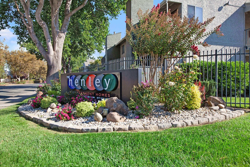 A sign for Tenley Homes is surrounded by flowers and plants at The Henley Apartments, California, 94585