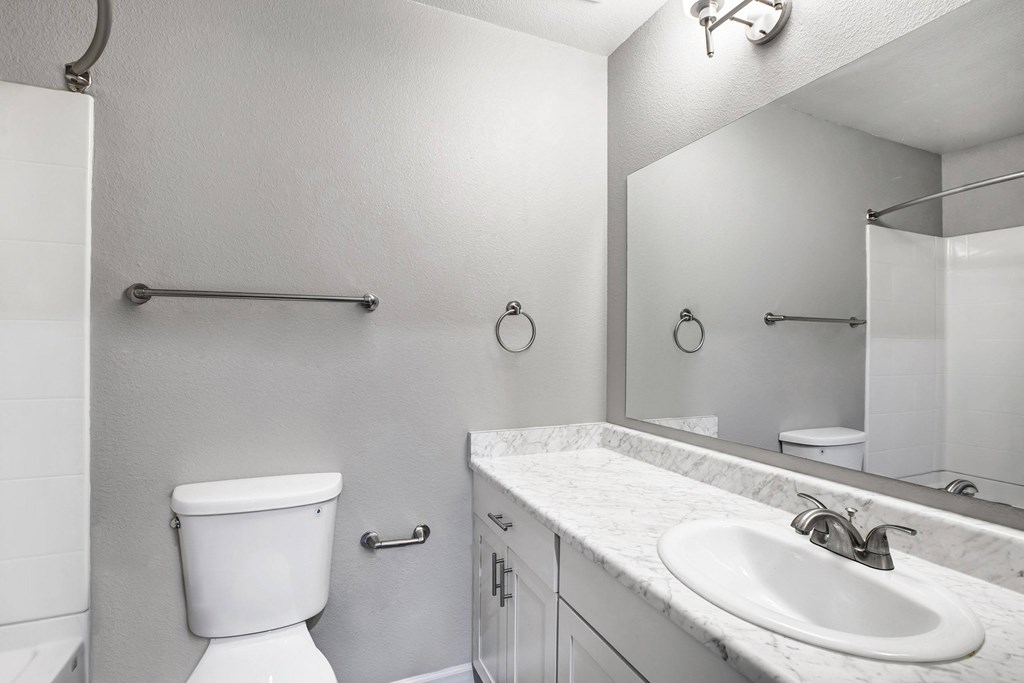 A white toilet is next to a sink in a bathroom at The Henley Apartments, Suisun City, 94585