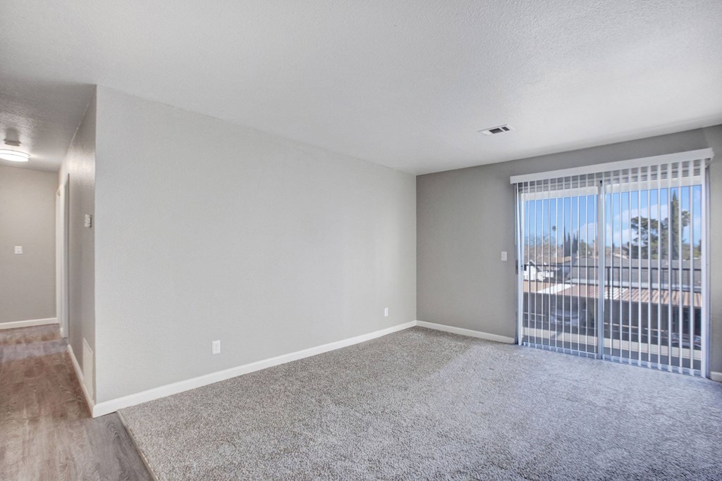 A room with a carpeted floor and a sliding glass door at The Henley Apartments, California, 94585