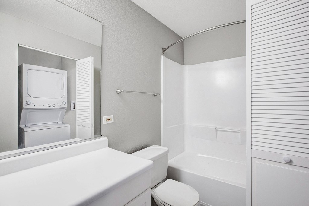 A white toilet sits next to a white sink in a bathroom at The Henley Apartments, Suisun City, CA, 94585