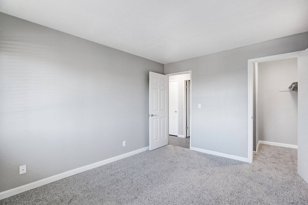 A room with a carpeted floor and a white door at The Henley Apartments, Suisun City, CA