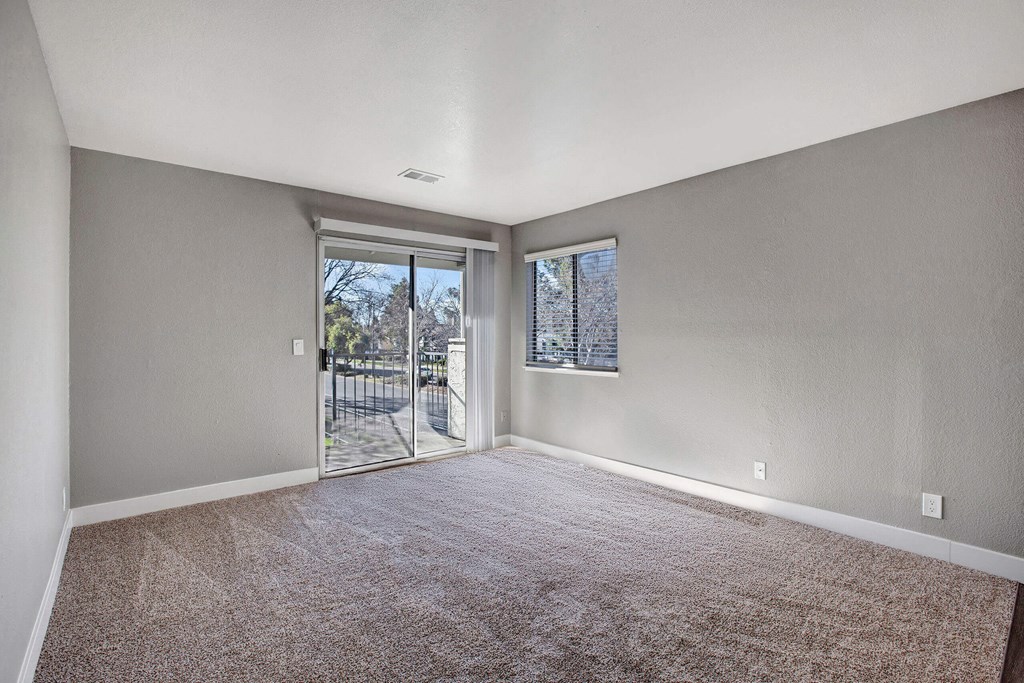 A room with a carpeted floor and a sliding glass door leading outside at The Henley Apartments, California