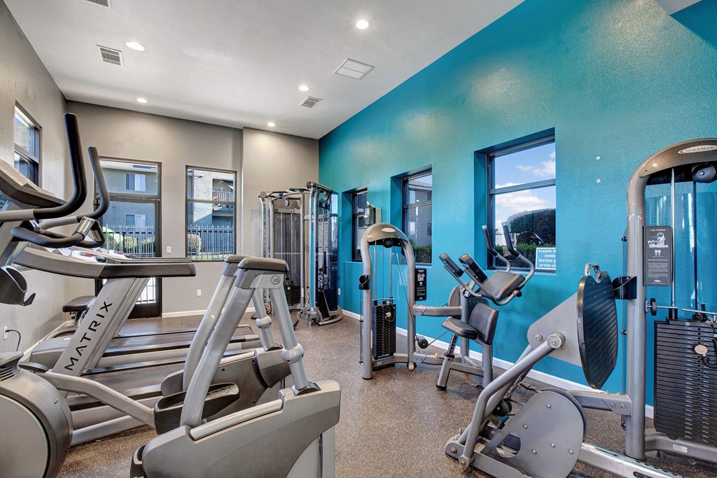 A gym with a blue wall and a treadmill at The Henley Apartments, California