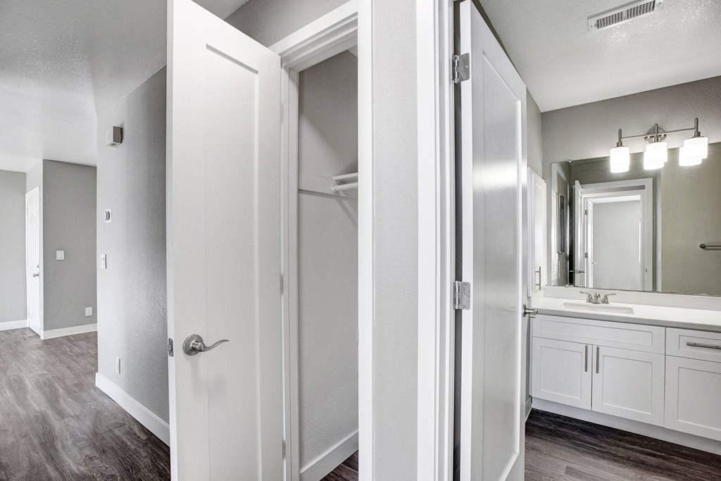 A white bathroom with a mirror and a sink at The Henley Apartments, Suisun City