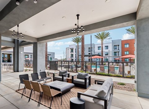 A patio with a black couch and chairs with a pool and buildings in the background at Ironwood Ranch Apartments,Maricopa,AZ,85138