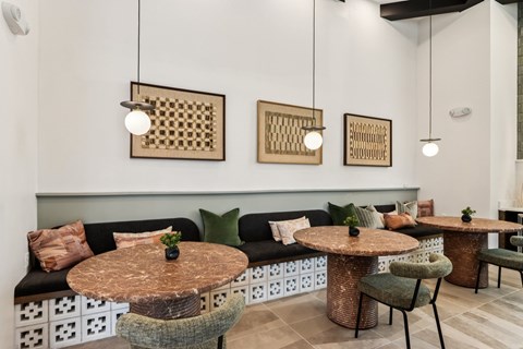 A modern dining area with a black sofa, round tables, and hanging lights at Ironwood Ranch Apartments,Arizona,85138