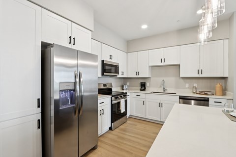 A modern kitchen with a stainless steel refrigerator and white cabinets.