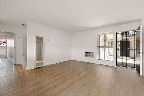 A spacious room with wooden flooring and white walls.