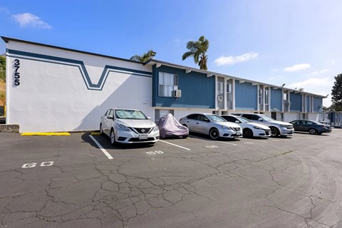 A parking lot with cars parked in front of a building with a blue and white exterior.