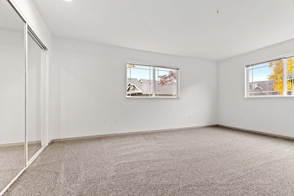 A room with a carpeted floor and two windows.at Maple Ridge, Washington
