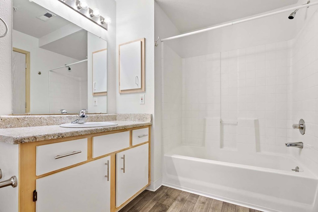 A white bathroom with a sink, mirror, and bathtub.at Maple Ridge, Vancouver