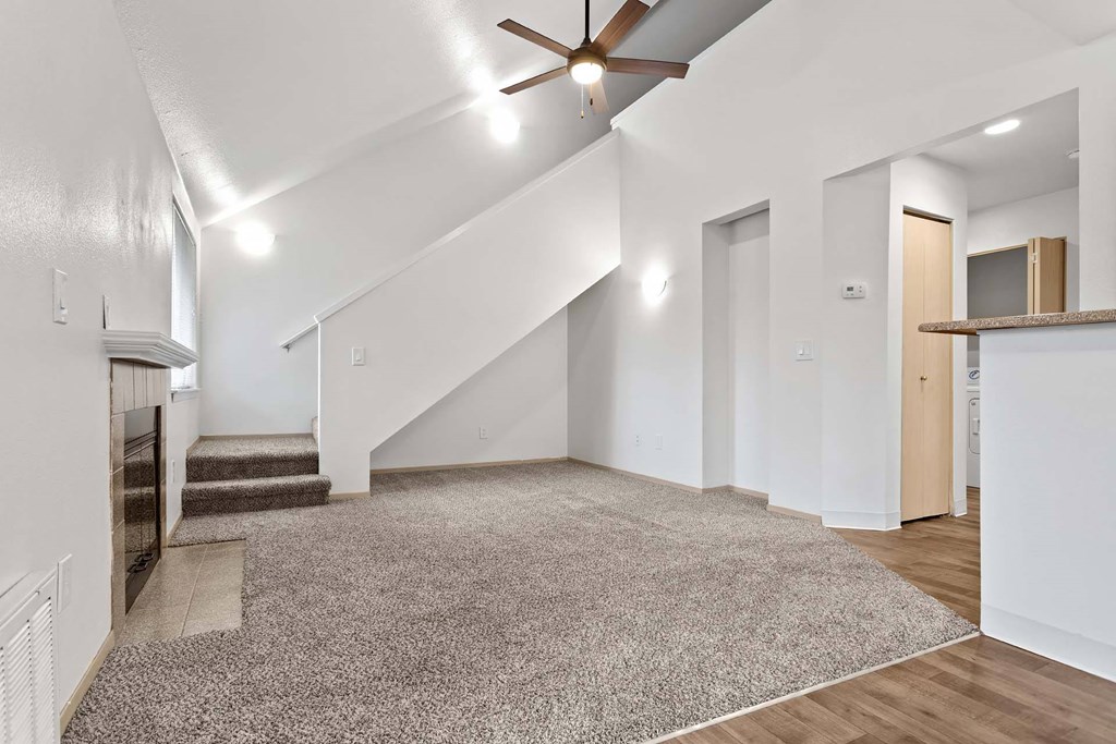 A spacious room with a staircase and a ceiling fan.at Maple Ridge, Washington
