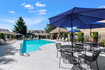 A pool area with a table and chairs and umbrellas.at Maple Ridge, Vancouver