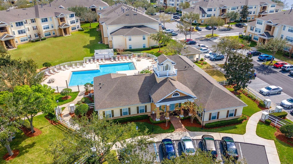 A bird's eye view of a residential area with houses, cars, and a swimming pool at The Villages on Millenia Apartments, Orlando, FL
