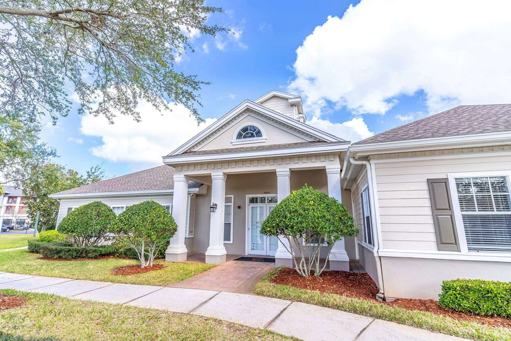 A house with a front porch and a tree in front at The Villages on Millenia Apartments, Orlando 32839